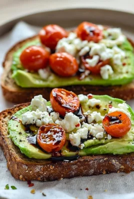Avocado toast topped with feta cheese and cherry tomatoes on a rustic wooden board
