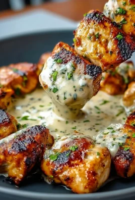 Grilled chicken bites served with creamy garlic sauce on a plate.