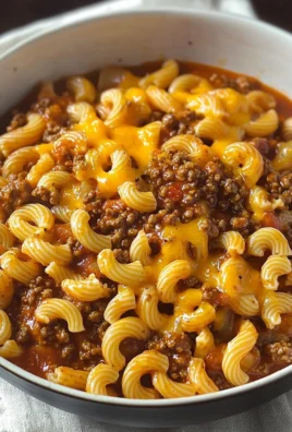 Plate of homemade hamburger helper topped with cheese and herbs.