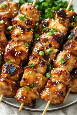 Delicious teriyaki chicken skewers on a grill, garnished with vegetables.
