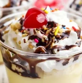 Delicious banana split pudding cups topped with whipped cream and cherries