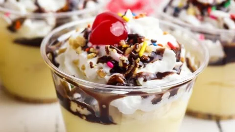 Delicious banana split pudding cups topped with whipped cream and cherries