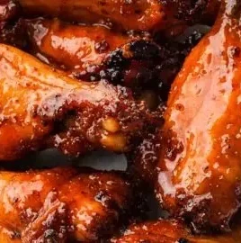 Plate of easy honey hot wings drizzled with honey sauce and garnished with herbs