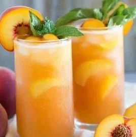 Refreshing easy peach lemonade served in a glass with fresh fruit.