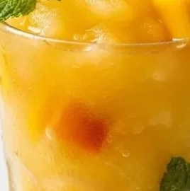Refreshing frozen mango peach lemonade in a glass with ice and fruit garnish