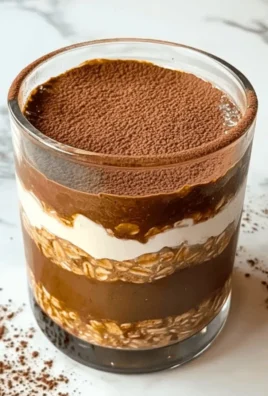 High Protein Tiramisu Overnight Oats served in a glass with coffee beans on top.