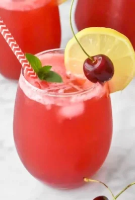 Glass of homemade cherry lemonade with fresh cherries and lemon slices