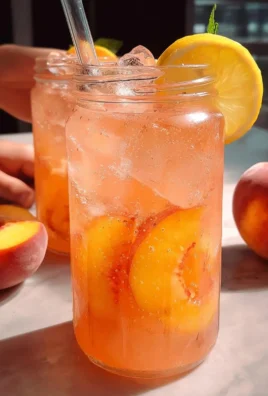 Freshly made peach lemonade in a glass with slices of peach and lemon