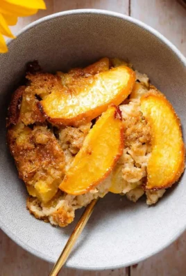 Delicious peach baked oatmeal served in a bowl, topped with fresh peaches and nuts.