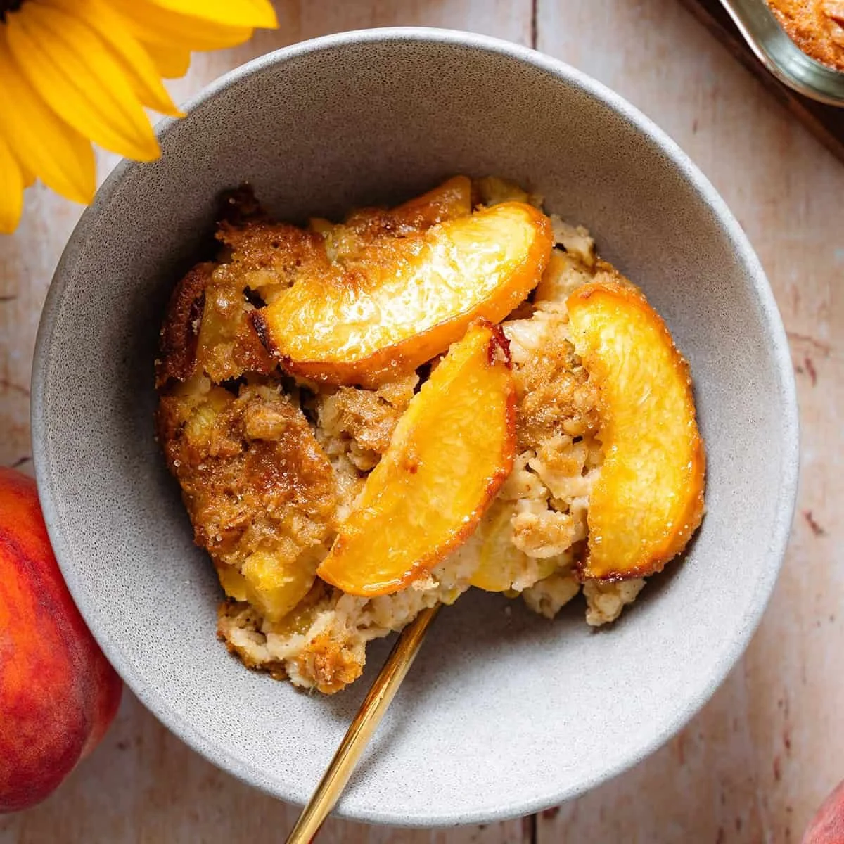 Delicious peach baked oatmeal served in a bowl, topped with fresh peaches and nuts.