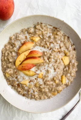 Bowl of Peaches & Cream Oatmeal topped with fresh peach slices and cream
