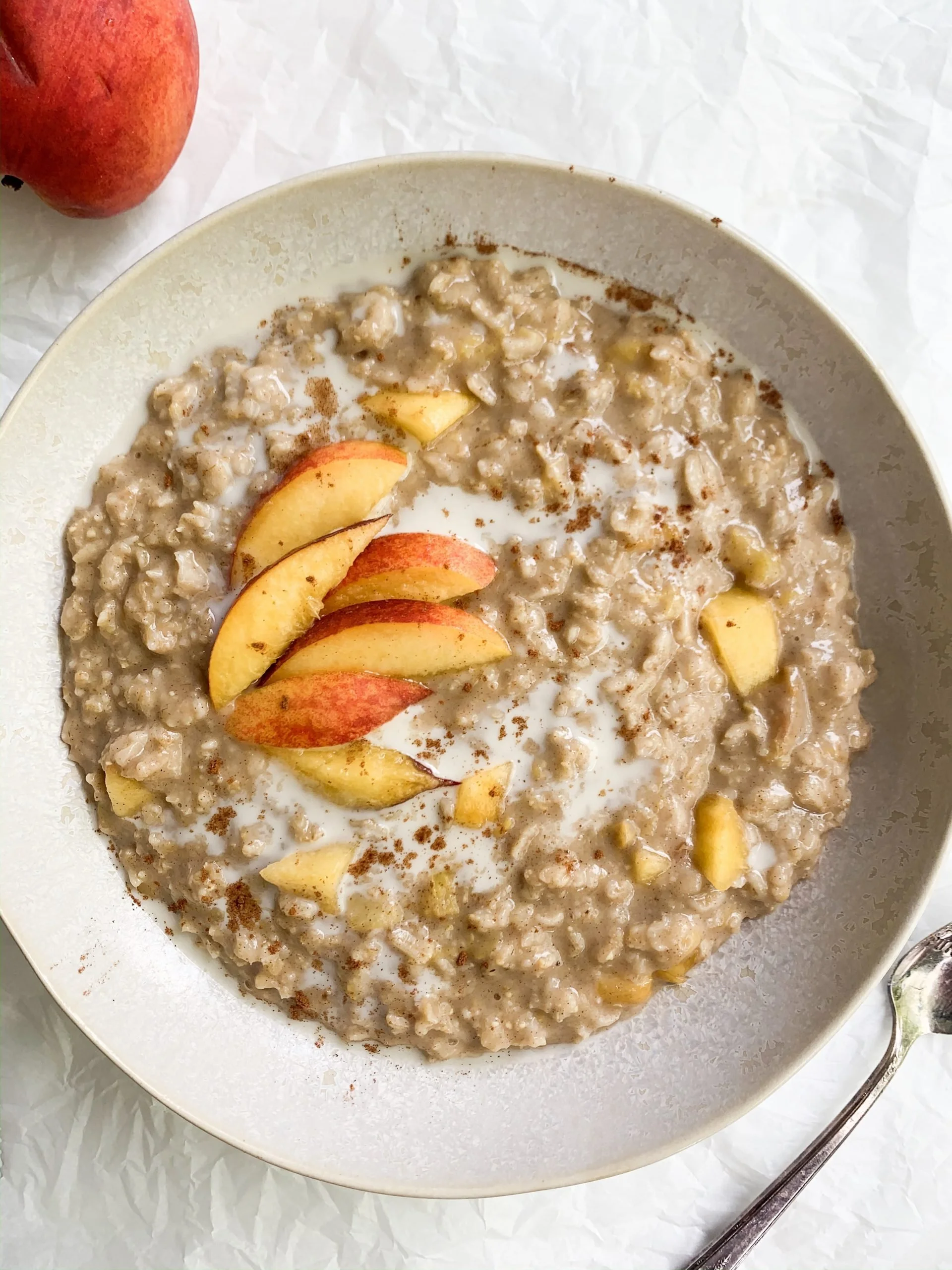 Bowl of Peaches & Cream Oatmeal topped with fresh peach slices and cream