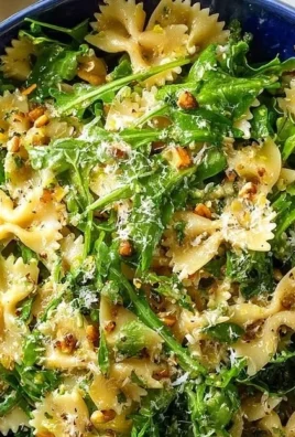 Tangy lemon arugula pasta salad in a bowl garnished with lemon slices