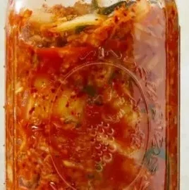 Homemade cabbage kimchi in a bowl with spices and vegetables