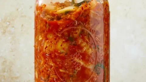 Homemade cabbage kimchi in a bowl with spices and vegetables