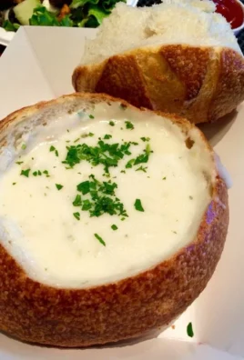 Delicious bowl of clam chowder topped with herbs and served with bread