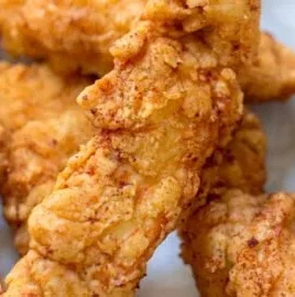 Crispy chicken tenders served with dipping sauce on a plate