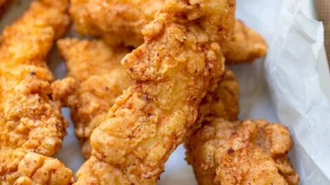 Crispy chicken tenders served with dipping sauce on a plate