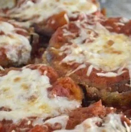 Delicious Easy Eggplant Parmesan served with fresh herbs and melted cheese.