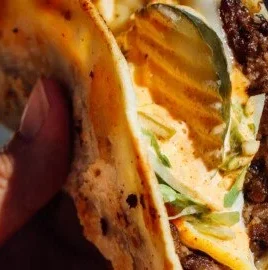 Delicious smash burger tacos served on a plate, showcasing the juicy beef and toppings.