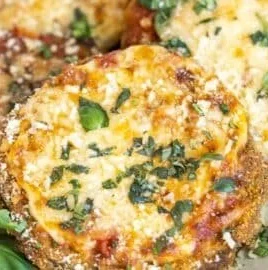 Delicious gluten-free eggplant parmesan served with fresh basil on top.