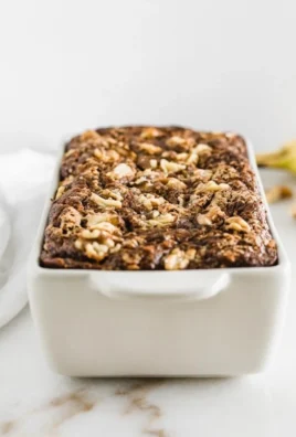 Healthy banana nut bread with walnuts and ripe bananas on a wooden table.