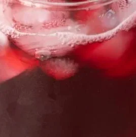 A refreshing glass of Hibiscus Iced Tea with vibrant red color and ice cubes.