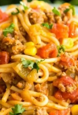 A vibrant bowl of Mexican Spaghetti garnished with fresh herbs and spices.