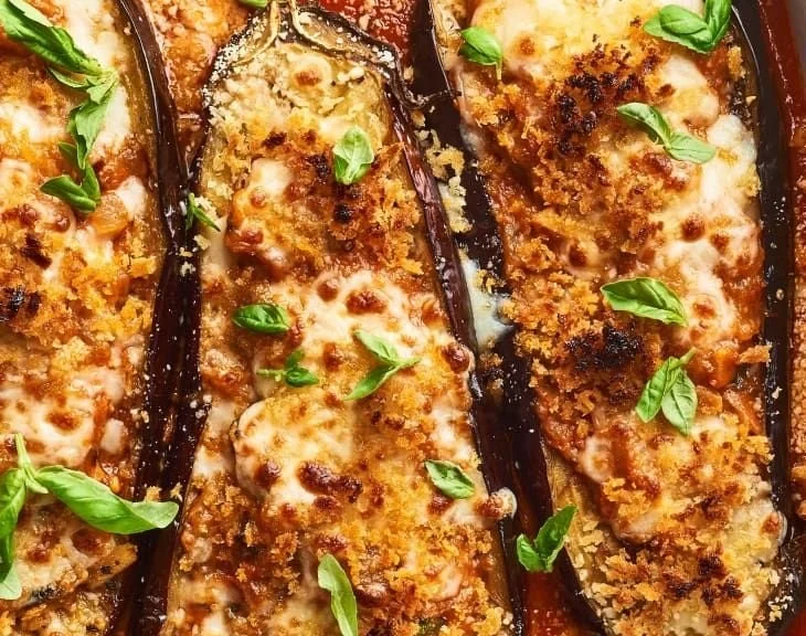 Stuffed Eggplant Parmesan topped with cheese and herbs in a baking dish