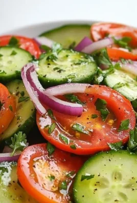 A vibrant summer cucumber and tomato salad with fresh herbs and dressing.