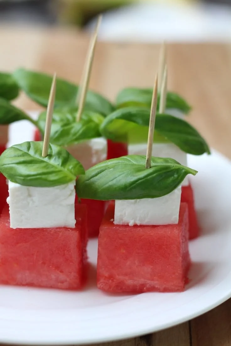 Watermelon skewers with feta cheese and fresh basil on a platter