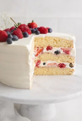 Sliced Berry Chantilly Cake topped with fresh berries and whipped cream