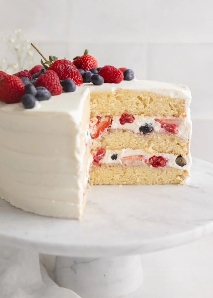 Sliced Berry Chantilly Cake topped with fresh berries and whipped cream