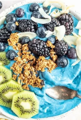 Colorful blue smoothie bowl topped with fresh fruits and seeds
