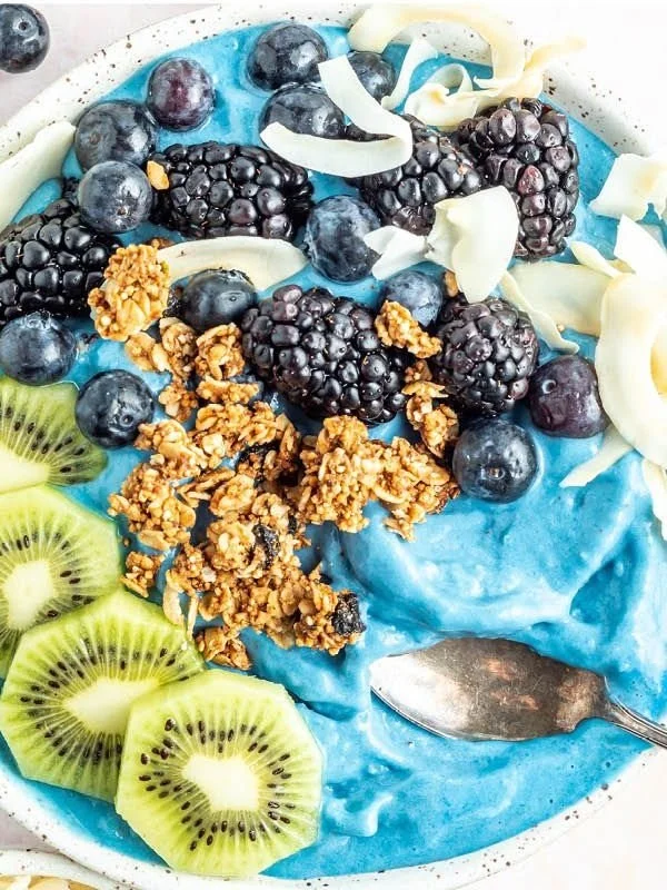 Colorful blue smoothie bowl topped with fresh fruits and seeds