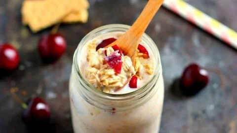 Bowl of cherry pie overnight oats topped with fresh cherries and cream