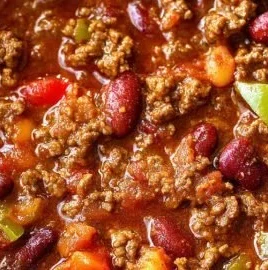 Bowl of easy classic chili topped with cheese and parsley, showcasing comfort food.