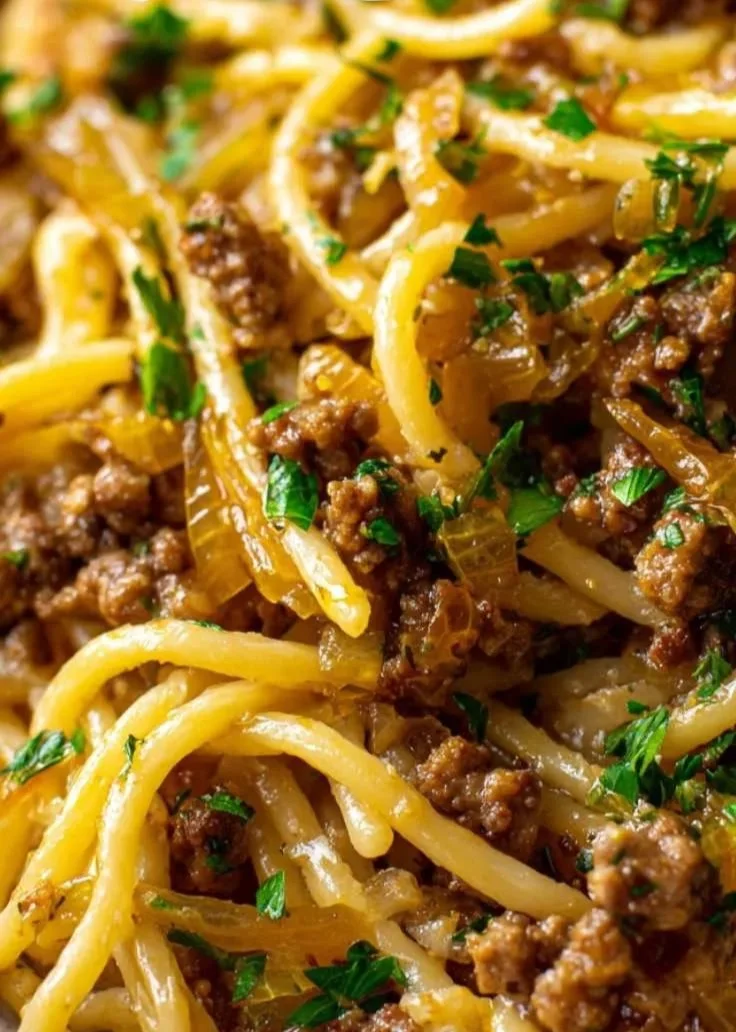 Plate of Garlic Butter Beef Pasta garnished with herbs and served with garlic bread.