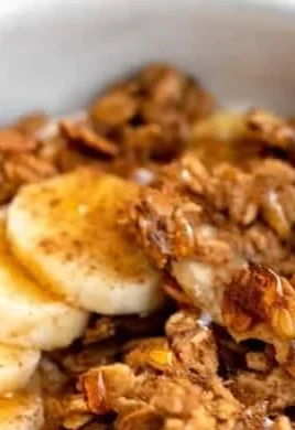 Bowl of gluten-free banana bread granola with sliced bananas and nuts