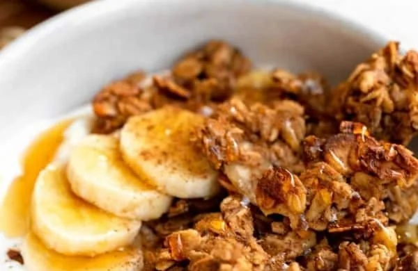 Bowl of gluten-free banana bread granola with sliced bananas and nuts