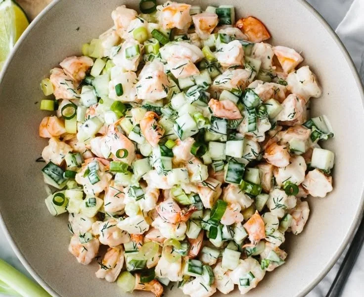 Healthy cucumber shrimp salad served in a bowl with fresh vegetables.