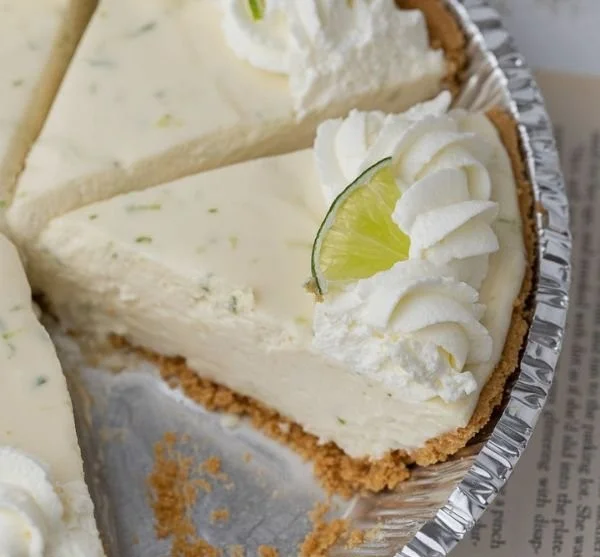 No bake key lime pie topped with whipped cream and lime slices on a plate