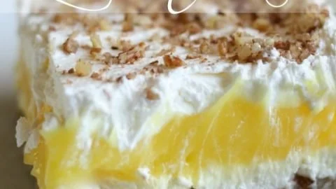 A slice of Luscious Lemon Delight dessert topped with lemon zest and whipped cream