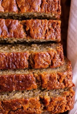 Loaf of moist banana bread topped with sliced bananas and walnuts