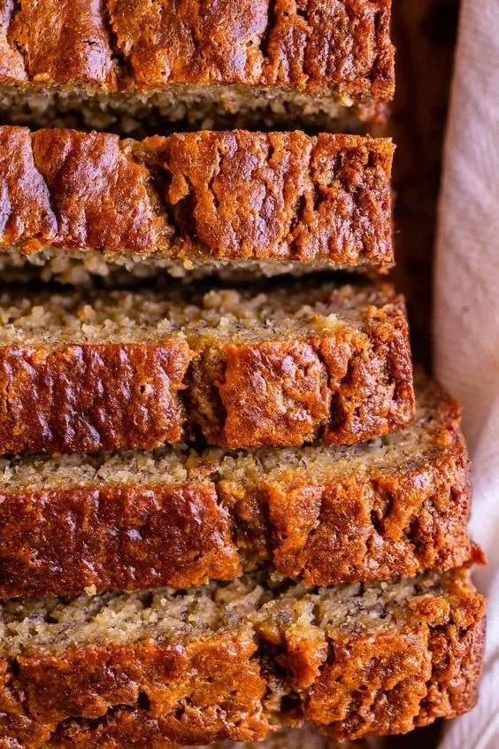 Loaf of moist banana bread topped with sliced bananas and walnuts