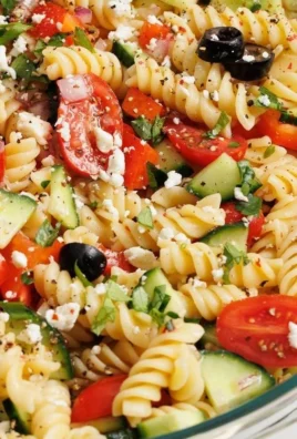 Colorful pasta salad with vegetables and dressing served in a bowl.
