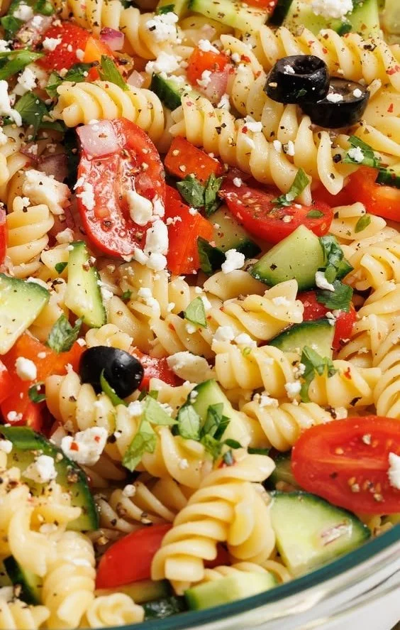 Colorful pasta salad with vegetables and dressing served in a bowl.