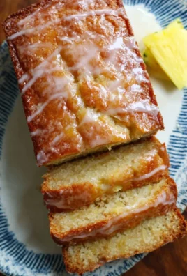 Freshly baked pineapple bread loaf, golden and inviting on a wooden cutting board.