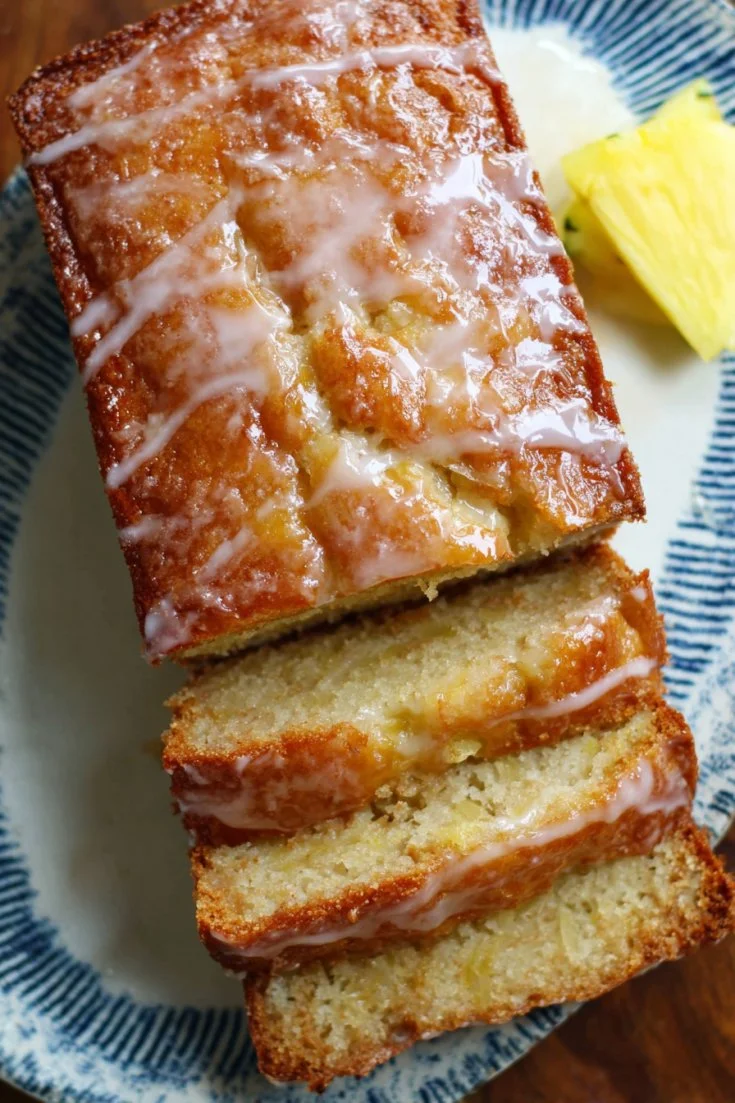 Freshly baked pineapple bread loaf, golden and inviting on a wooden cutting board.