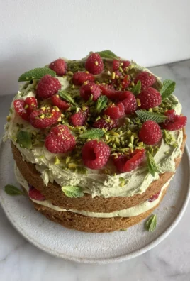 Slice of Pistachio Raspberry Cake with fresh raspberries and chopped pistachios